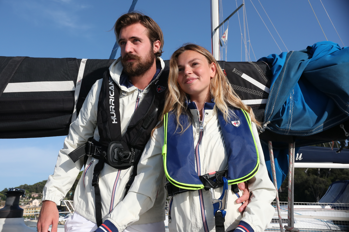 Coppia a bordo di una barca a vela indossa giubbotti di salvataggio Veleria San Giorgio, dispositivi nautici conformi alle normative di sicurezza per barche e gommoni.